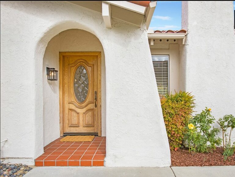 entry to home showing clean spanish tile, wood door, and carriage light